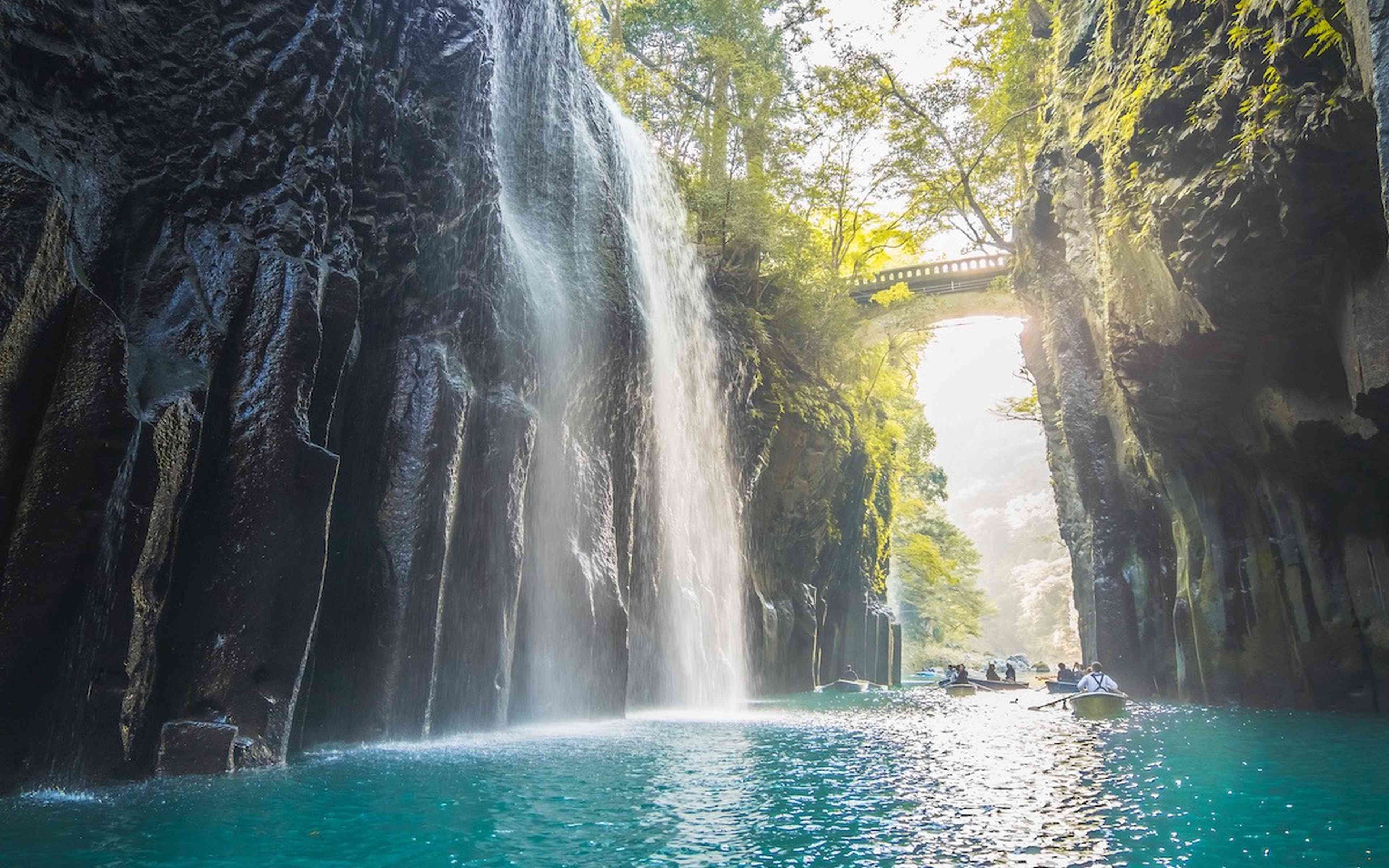 A waterfall pouring into a gorge, with rowing boats